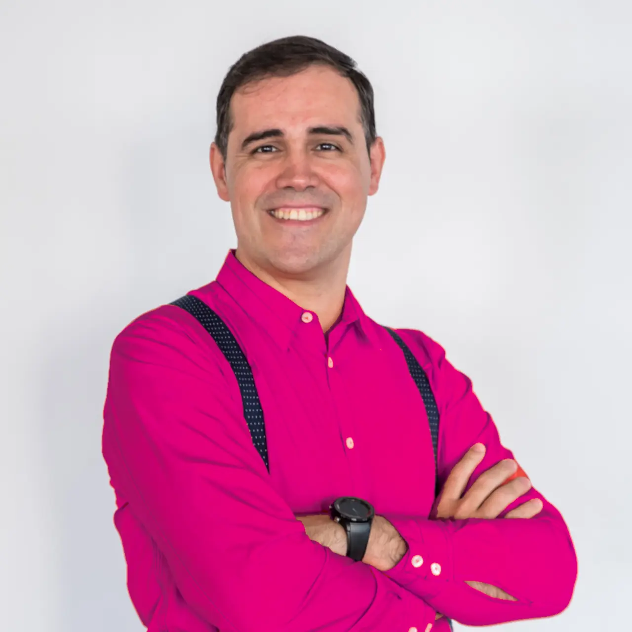 Imagen de Mánu Fosela, con camisa magenta electrico y tirantes azul oscuro. De lado, con brazos cruzados. La imagen ocupa la mitad izquierda de la pantalla